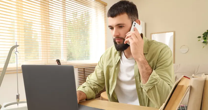 Image of a man on a phone call at his desk