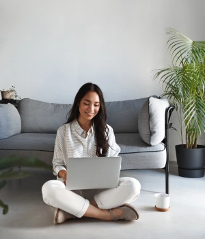Image of a woman smiling at her laptop during an in-network virtual therapy session for affordable addiction care