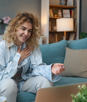 Image of a woman smiling at her laptop during a confidential admissions consultation to start her recovery journey