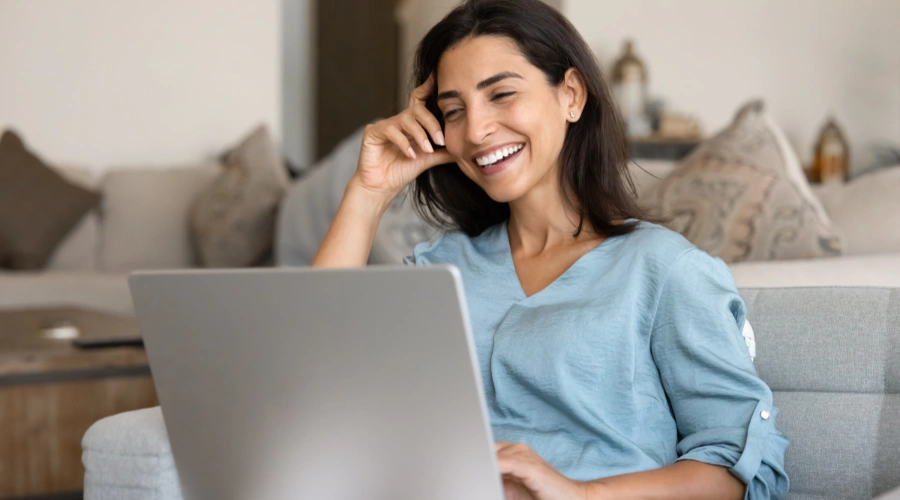 Image of a woman smiling at her laptop feeling confident as she begins her virtual IOP program with Shanti Recovery & Wellness